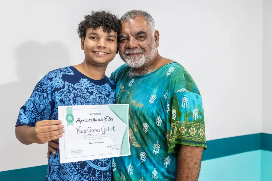 Kauã segurando o certificado de aprovação na ETEC, abraçado a um familiar